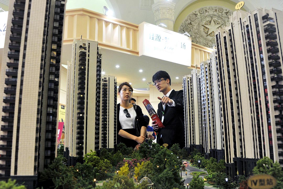 中國上海一個房地產展銷會，一名銷售員在住宅模型前向顧客推銷樓盤。攝：Stringer/REUTERS