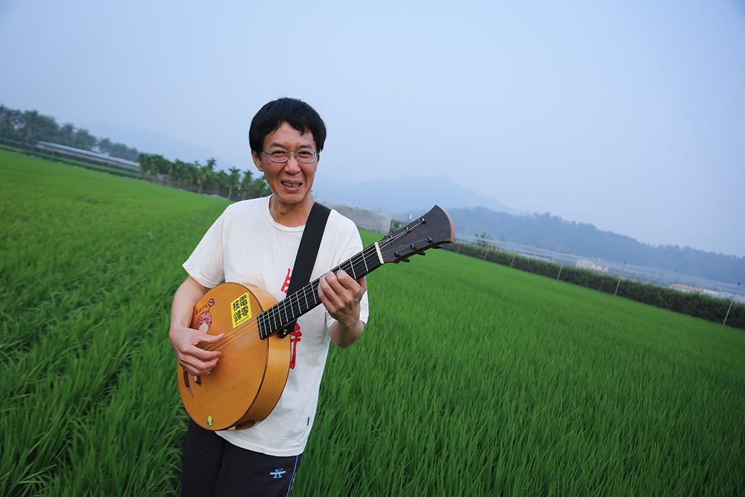 林生祥在高雄美浓家附近的田野演奏乐器。