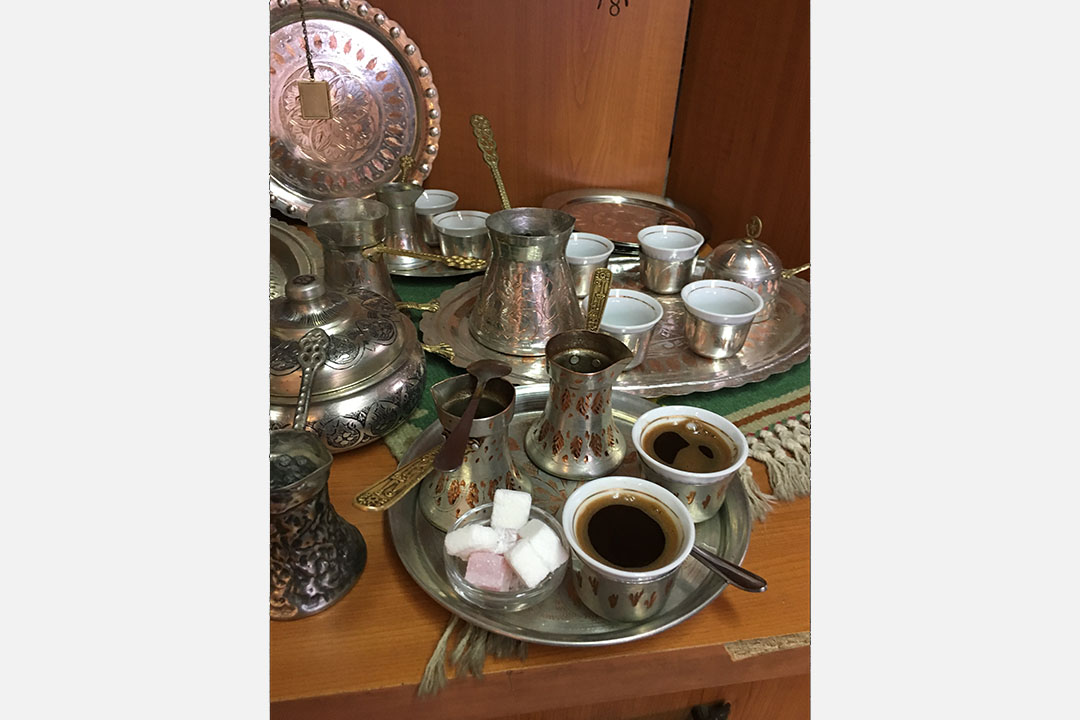džezva 的咖啡套装，银色托盘上有盛满咖啡的带耳铜瓶、方糖罐及一对小瓷杯。