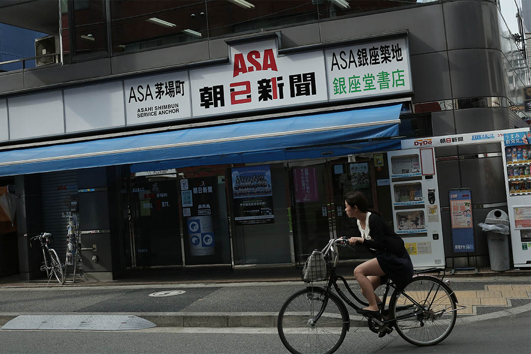 2016年8月3日,日本東京,一個女士騎着單車駛過朝日新聞茅場町辦公室。