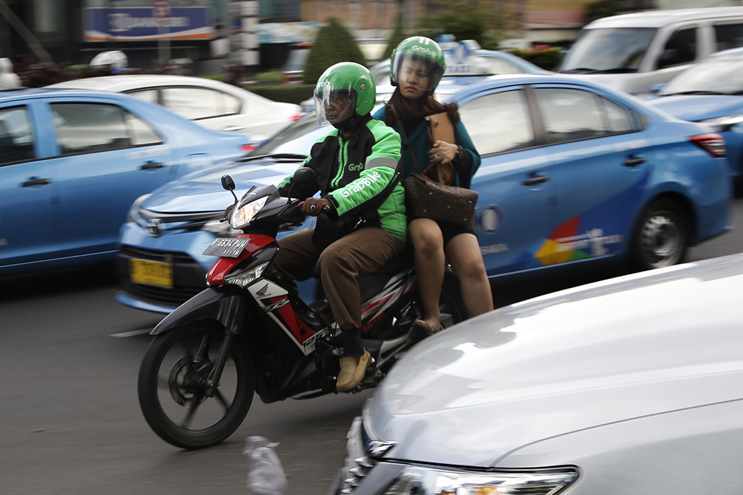 2016年4月29日,印尼雅加達,一名GrabBike的司機載著乘客在街頭穿行。