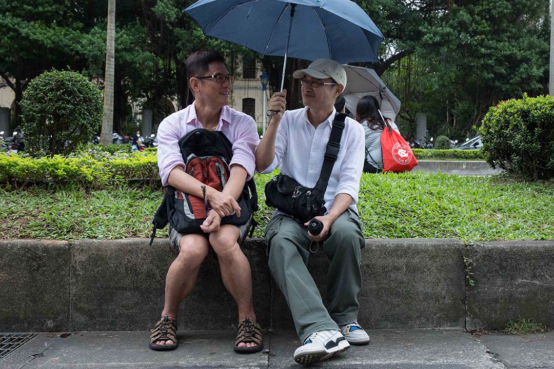 图为2016年台湾同志游行,一对同志情侣在路边休息聊天。