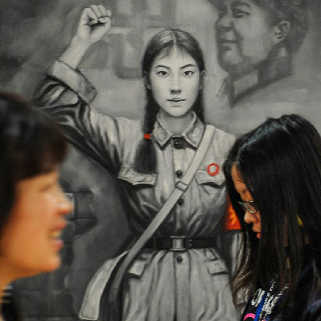 过去于上海举办的一个艺术展览内,一幅文化大革命时期的红卫兵画像前,一名年青女孩和一名妇女迎面走过。