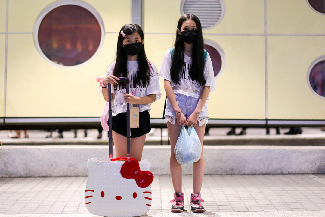 兩個近140公分高的小女生,拖着一個HelloKitty大頭造型的行李箱,準備接受訪問。