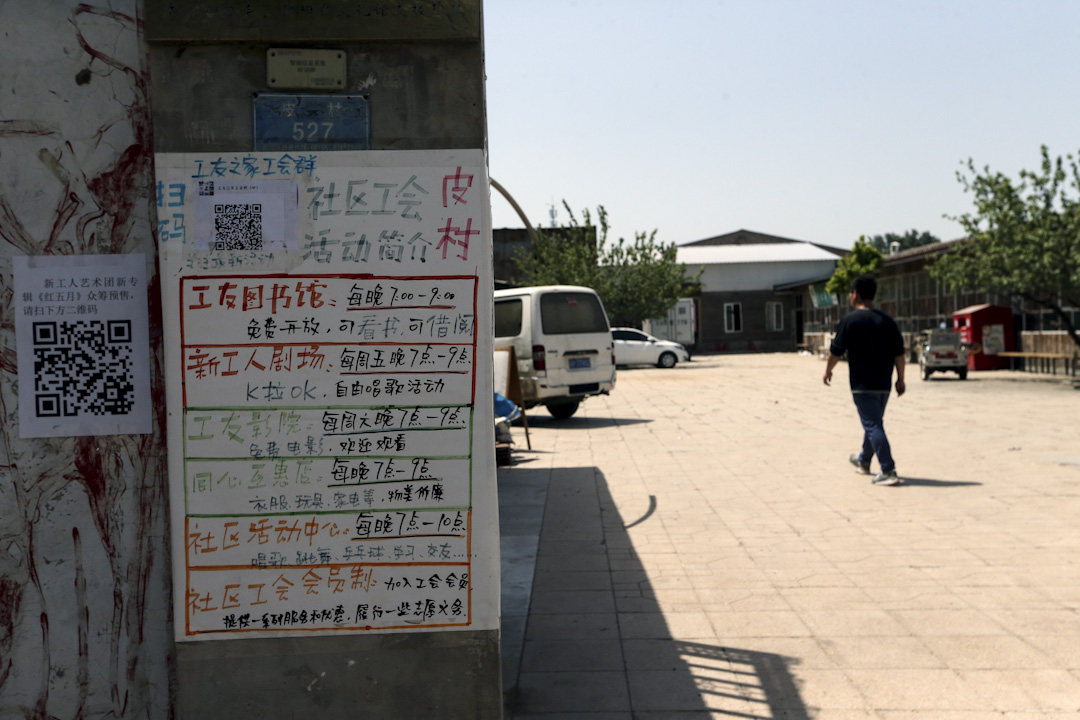 皮村社區文化活動中心的水泥門柱張貼著廣告體寫的圖書館、影院開放時間。