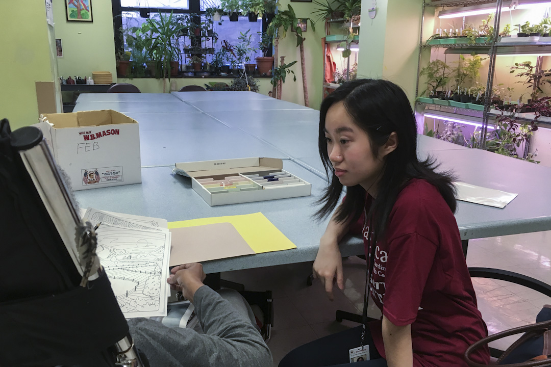 哥伦比亚大学的一位志愿者,正在陪同一位居民下棋。
