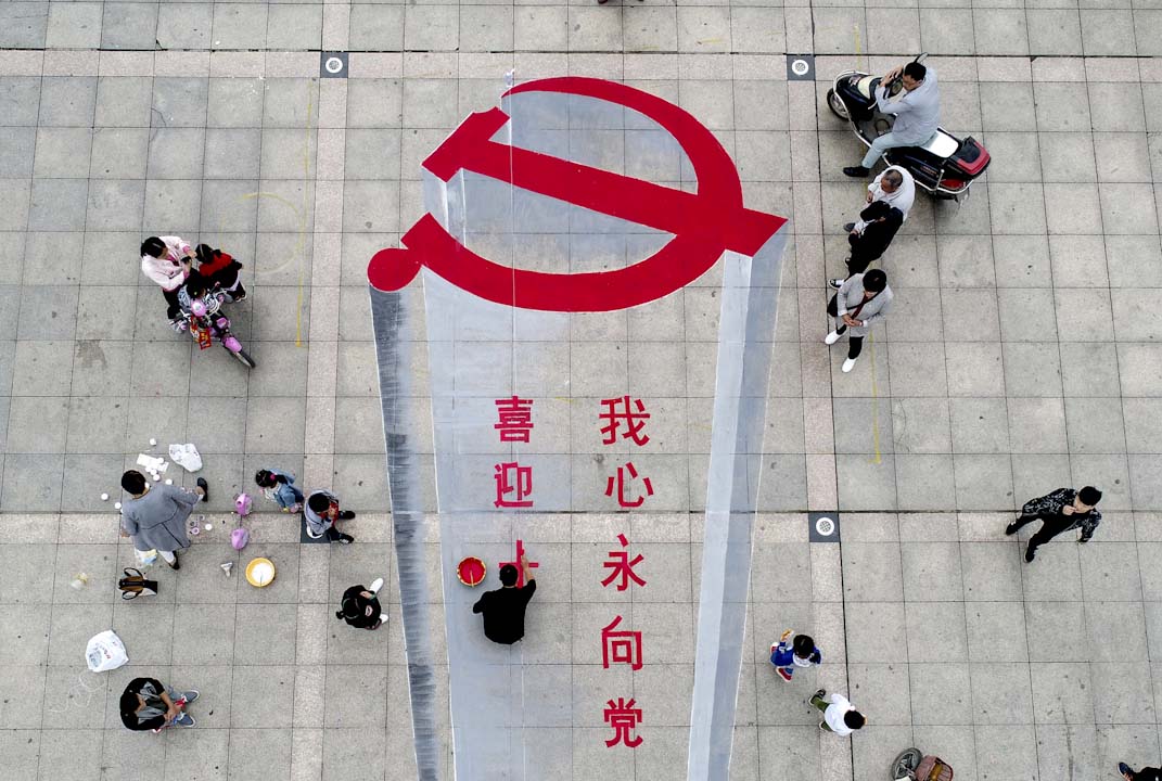 2017年10月6日，一名男子在河南的一幅地上繪畫中國共產黨的黨徽，以迎接10月18日中共十九大的來臨。
