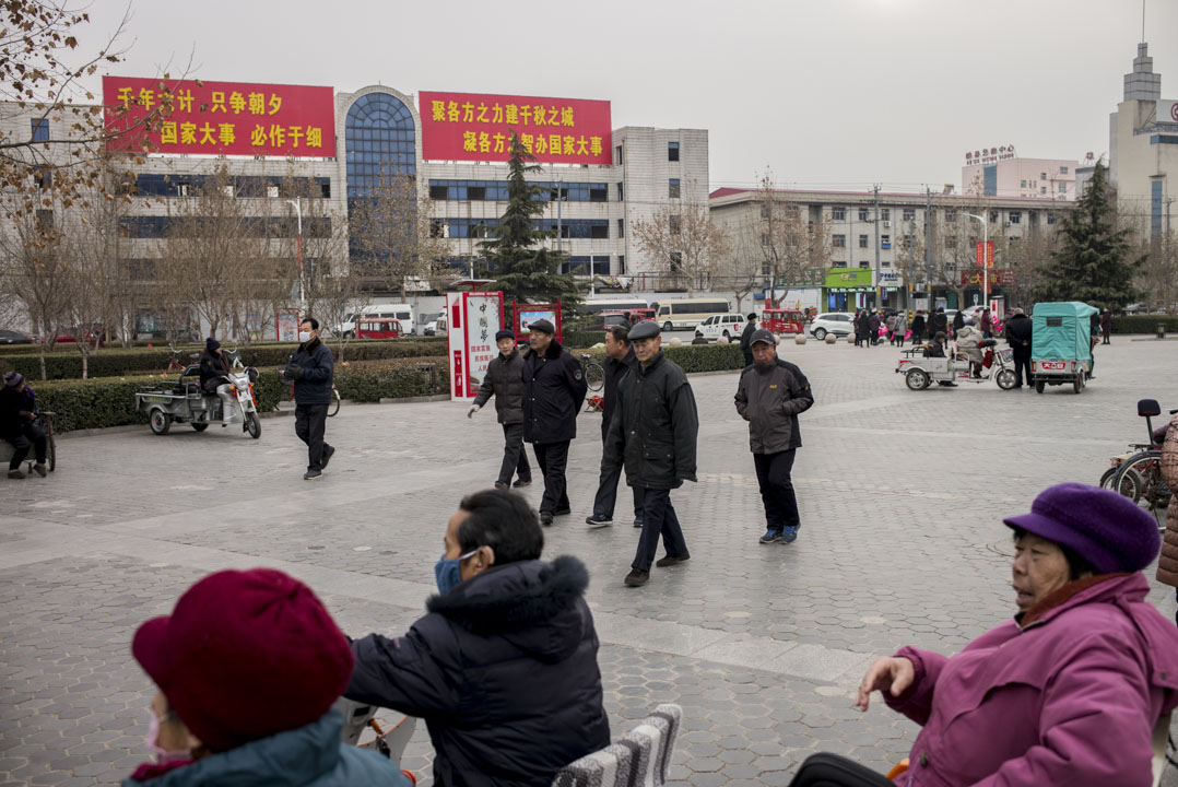 市民在雄縣政府大樓前的廣場消磨時間,背後有設立河北雄安新區的大字標語。