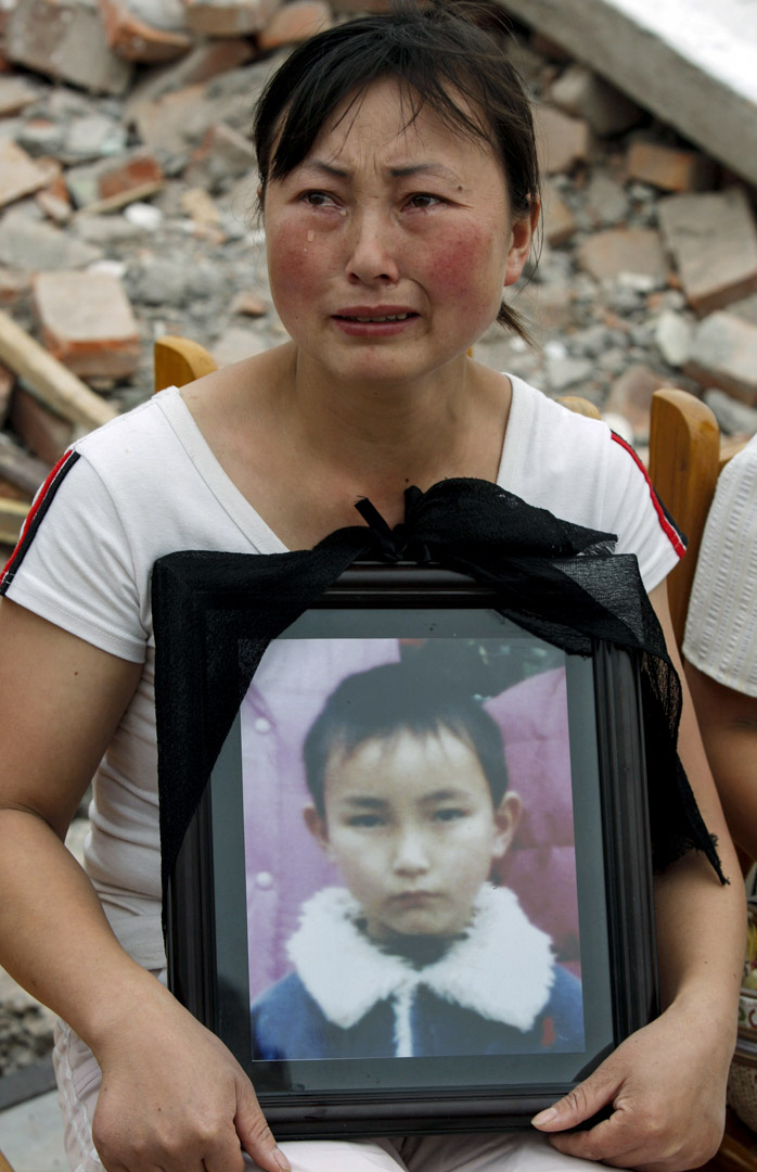 2008年5月22日,四川地震后富新二小的废墟上,刘孟瑛捧着儿子的遗照。