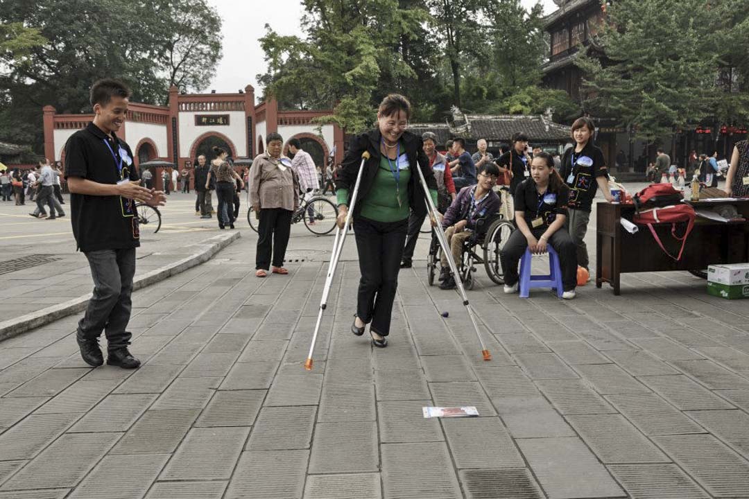 残障人士最终都要与家人在社区里过活,香港复康会希望“可以改变社区去帮助残障人士,而不是教残障人士怎样上两级楼梯”。图为香港复康会在都江堰举办活动。