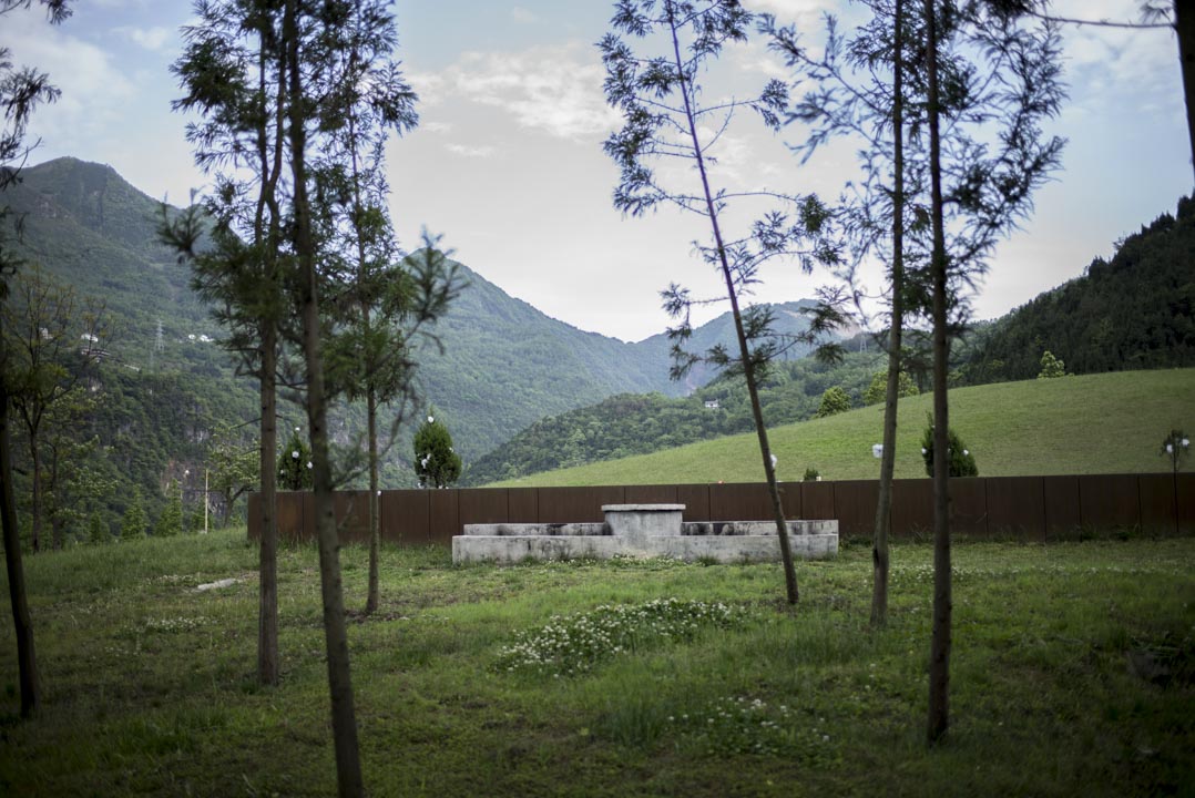 “就是这片小山坡,当年的北川中学和孩子们,就埋在下面,这前面的绿草坪,就是以前的操场。”北川县城一名老人。
