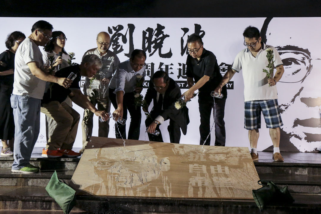 支联会代表向印有刘晓波肖像,以及抗争、自由、希望等字眼的画板洒水,寓意祭奠刘晓波。