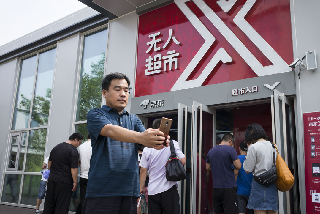 京東無人超市門口，參觀者正聚在一起研究怎樣進去。