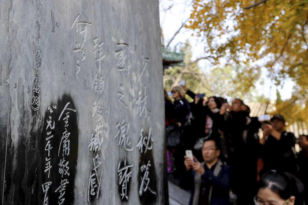 2018年11月2日,河南嵩山少林寺,民眾在少林寺天王殿門前的金庸石碑送上菊花,悼念逝世的金庸。