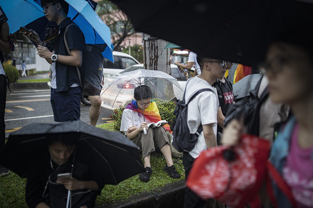 2019年5月17日，台北立法院外挺同團體發起集會，參加者在大雨下舉傘等候投票結果，一名支持者在看書。