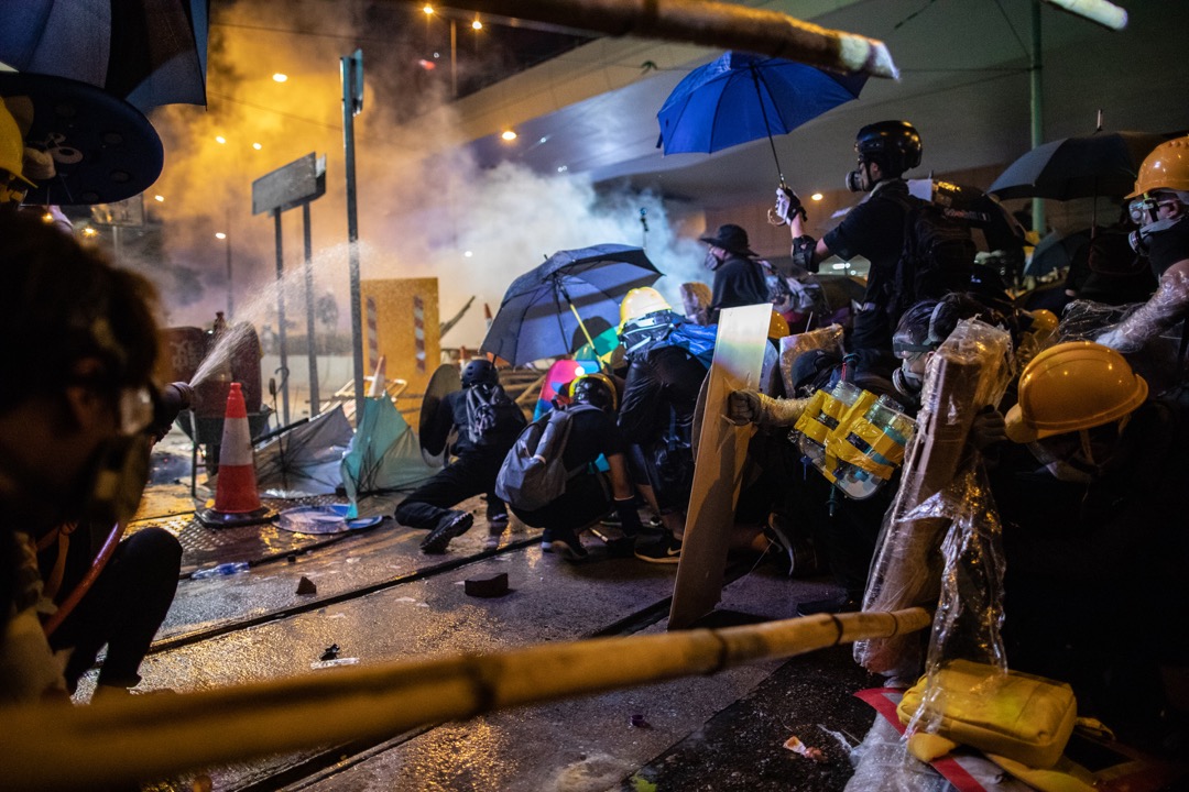 示威者以雨傘和消防喉作掩護,預備抵擋警察下一波的催淚彈。