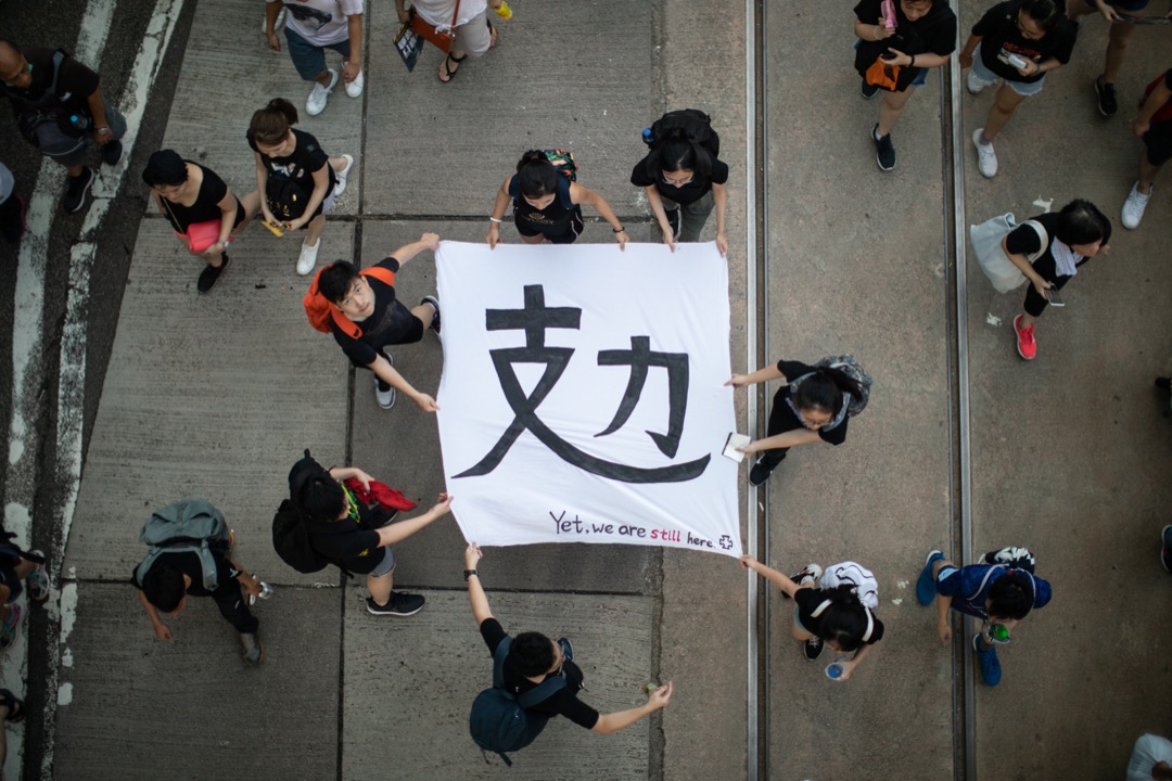 2019年7月1日，民阵发起七一大游行，有参加者拿著写有“攰”（累）字的横幅。