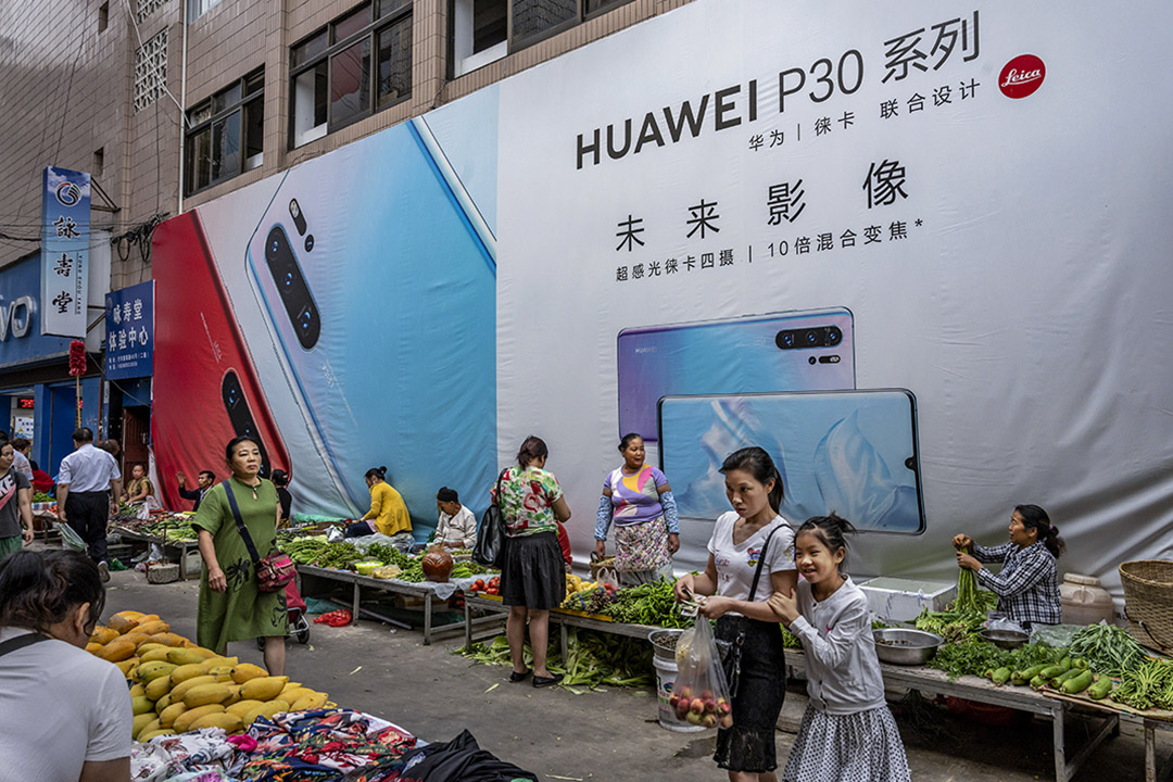 2019年6月1日，雲南省的一個市場，一名婦女與她的女兒在華為智能手機的廣告牌前走過。