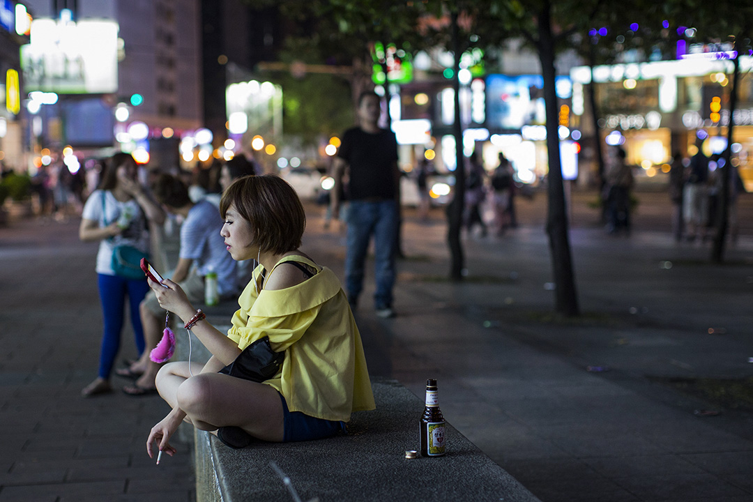 一名女子在台北的街頭看手機及抽煙。