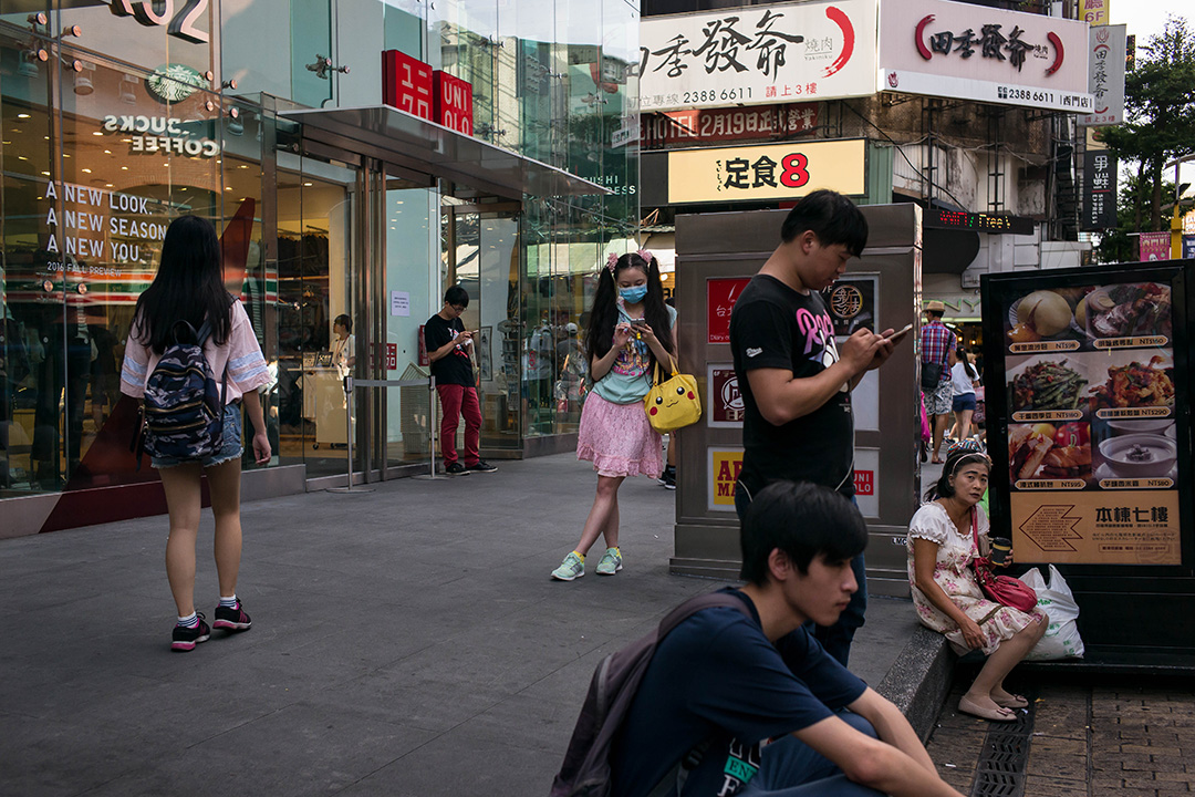 2016年8月8日,人们在台北西门看他们的智能手机。