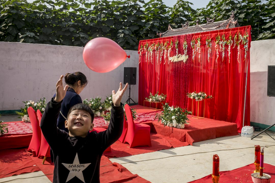 院子裏有一座紅色舞台,是李總團隊當天凌晨搭好的。一條紅毯T台,圍繞着仿真的白色玫瑰,象徵愛情的純潔。