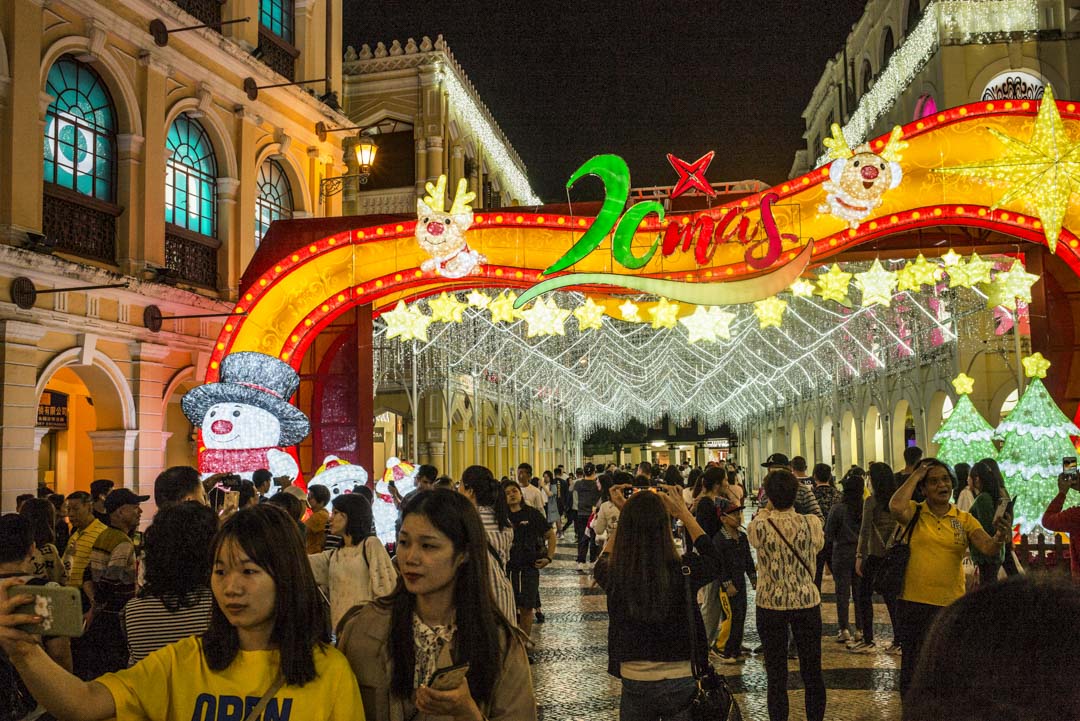 2019年12月18日,旅客在庆祝澳门回归20周年的装饰前拍照。