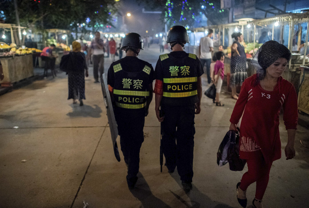 2017年6月25日，在开斋节假期的前一天，警察在中国新疆维吾尔自治区喀什市清真寺附近的夜市里巡逻。