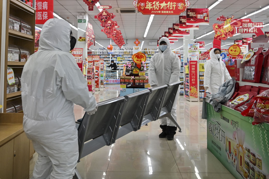 2020年1月25日，戴著防護服和口罩的藥房工作人員在武漢為顧客服務。