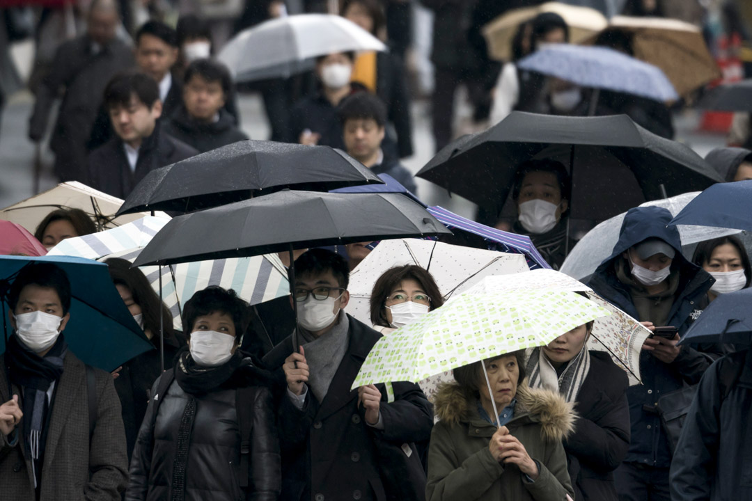 2020年2月13日,東京,戴著口罩的市民拿著傘步行在路上。