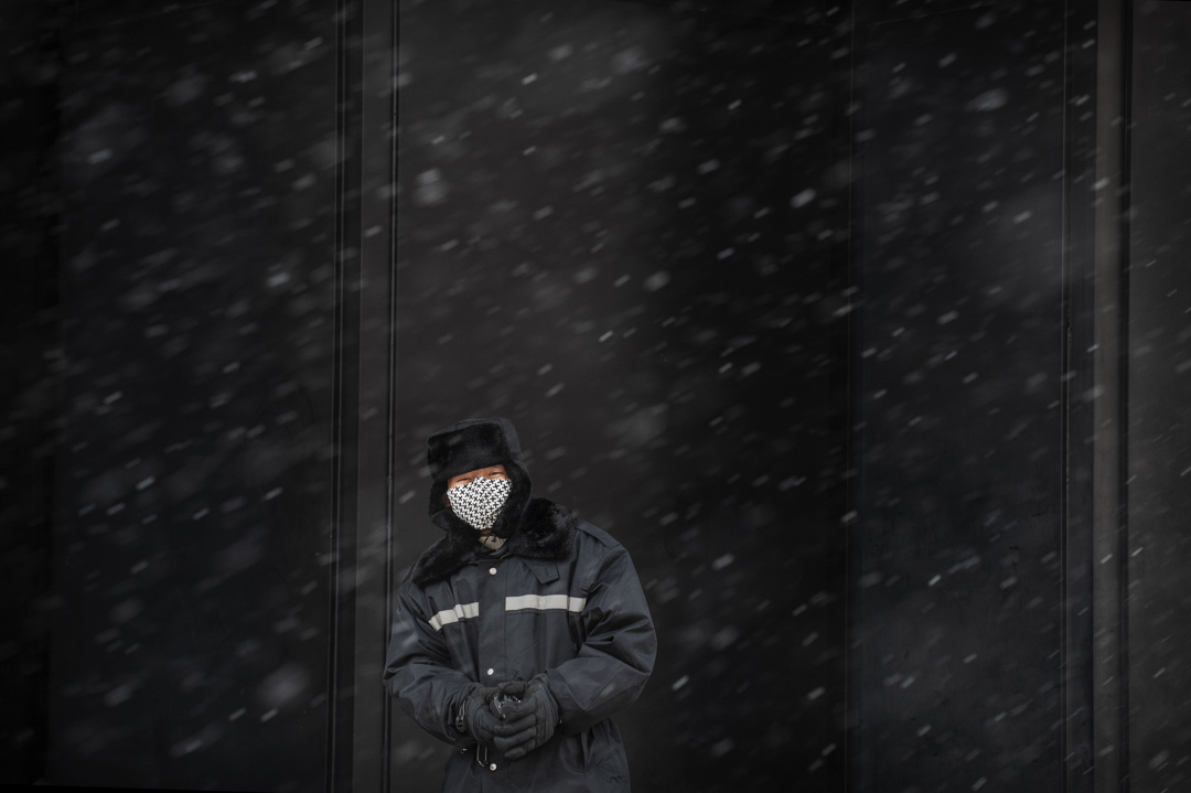 2020年2月14日,北京降雪,一名保安在幾乎空曠的購物區站崗並戴著防護口罩。