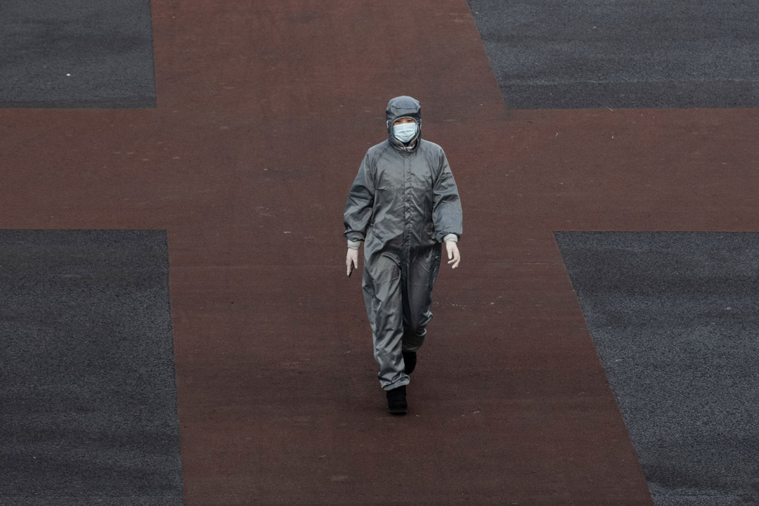 2020年2月8日,北京一名穿著防護服和口罩的中國婦女越過一條空曠的街道十字路口。