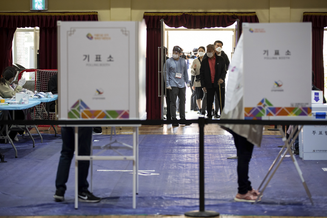 2020年4月15日,南韓舉行四年一度的國會選舉,首爾一個票站外有佩戴口罩、戴上即棄手套的選民排隊,等候接受體温檢測,以進入票站投票。