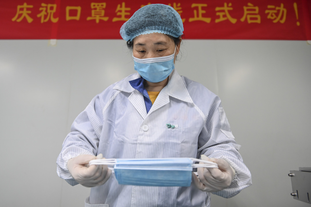 2020年4月2日,一名工人在中國廣州的一家工廠檢查在生產線上的口罩。