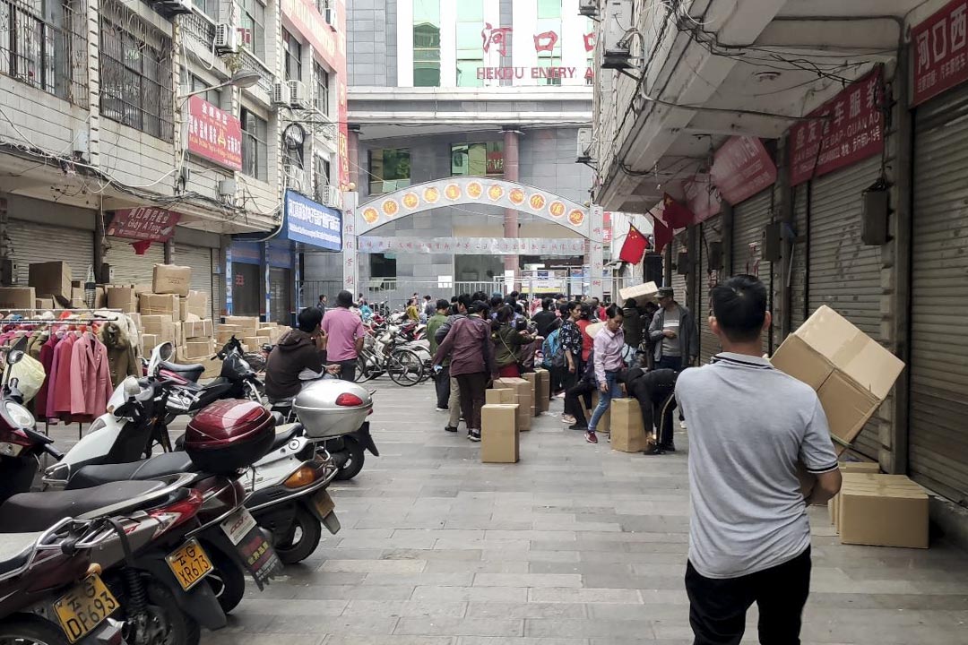 雲南紅河州河口縣的海關關口，人們排隊將口罩送向另一邊的越南。 