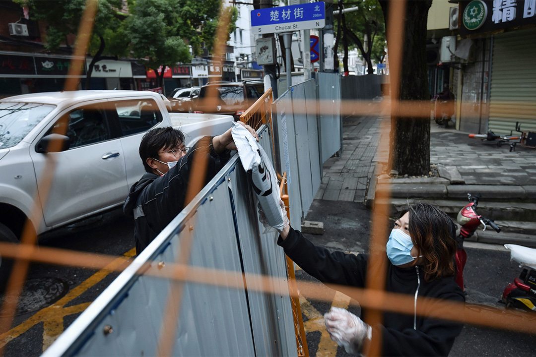 2020年2月26日湖北省武漢市,一名送貨騎手將包裹交給被隔離的居民,以預防2019冠狀病毒。