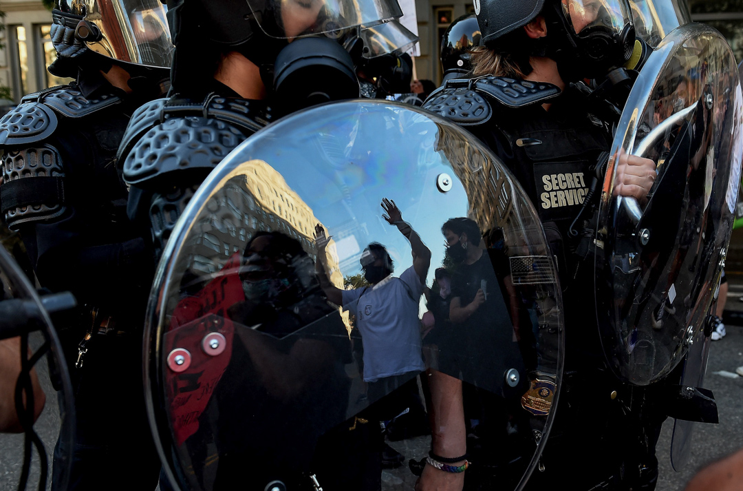 2020年6月1日白宫附近一个公园,一名示威者举高双手站在防暴警面前。
