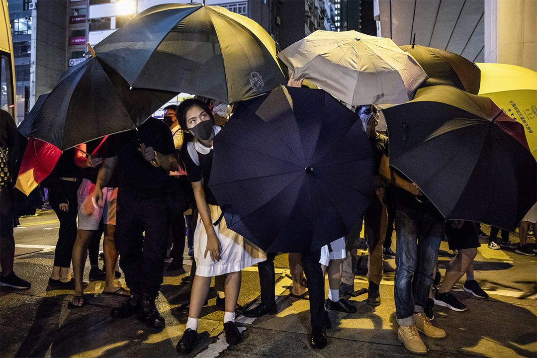2019年9月3日,一名穿著校服的示威者在太子警署门外示威,在雨伞阵内向外眺望。