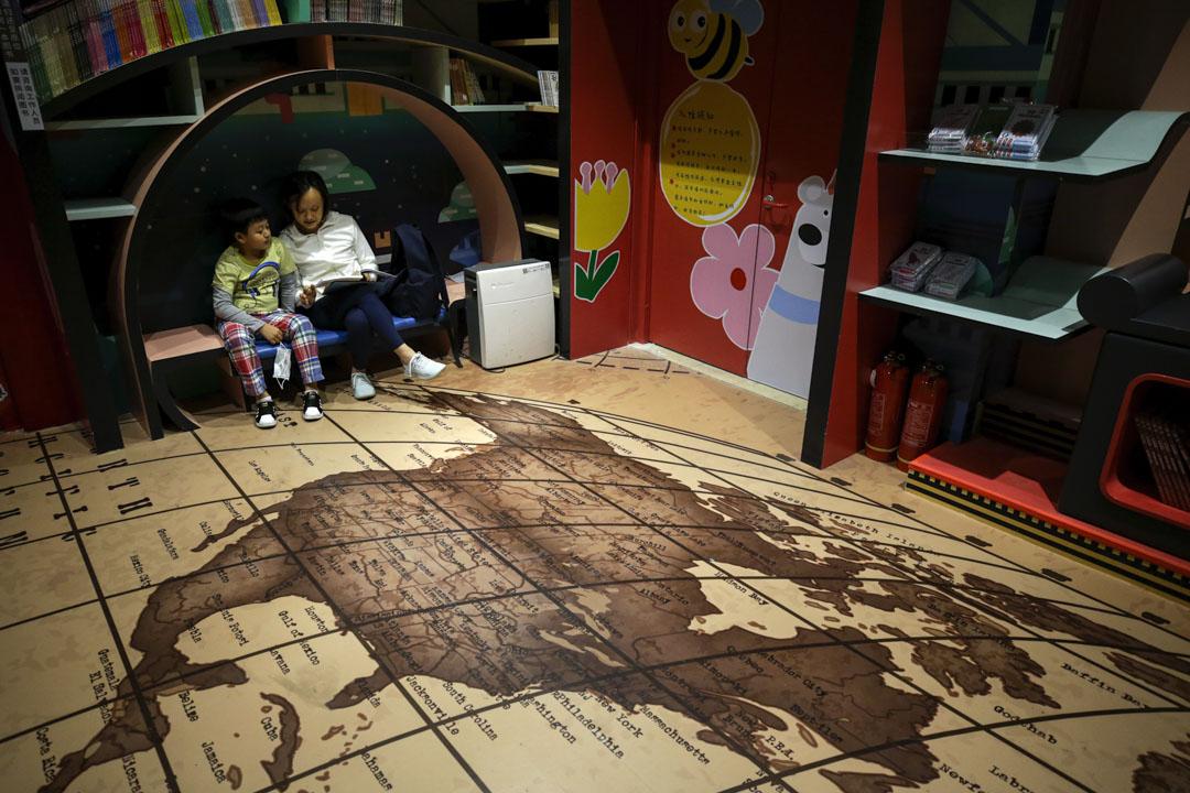 2020年5月17日,一名女士和一名兒童在北京一家書店看書,店內地面有的一張地圖顯示著北美和中美洲。