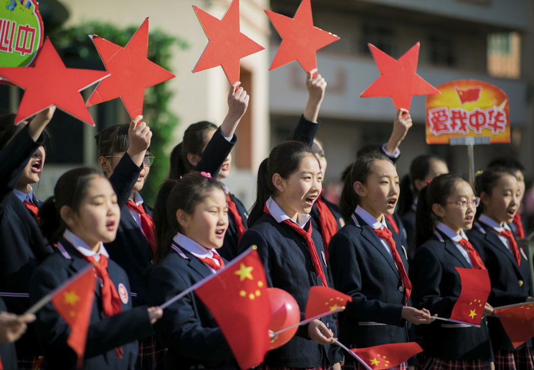 2019年2月28日,中国内蒙古自治区呼和浩特市,学生们在表演名为“我和我的祖国”的歌曲时举著中国国旗。