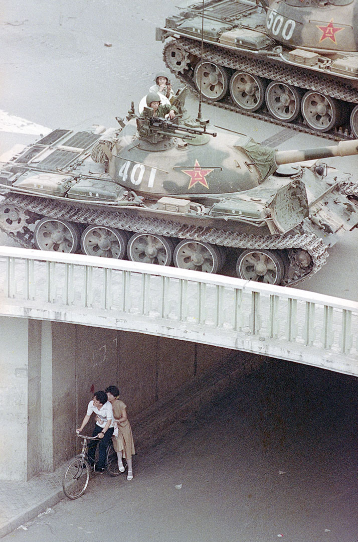 1989年6月5日,一對中國情侶騎著單車以地下通道作掩護,坦克在橋上行走。