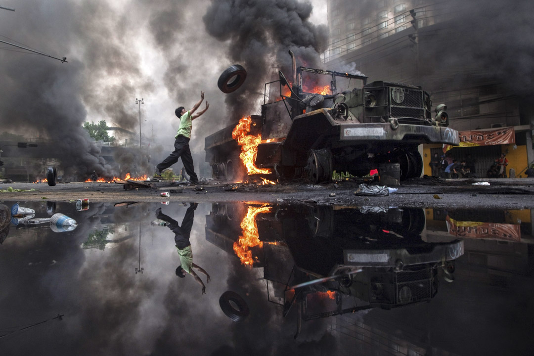 2010年5月16日曼谷,反政府抗議者紅衫軍投擲輪胎往被燒的卡車。