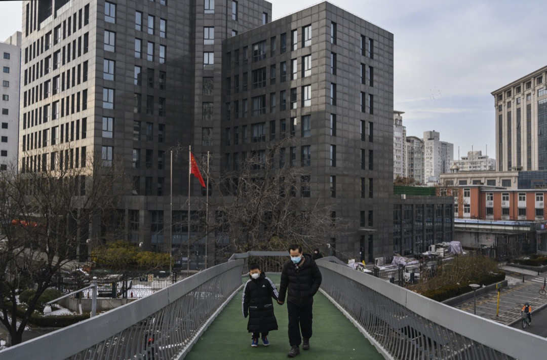 2020年2月8日,一名戴著口罩的男子拖著一位戴著口罩的小孩走過一個住宅區的街道。
