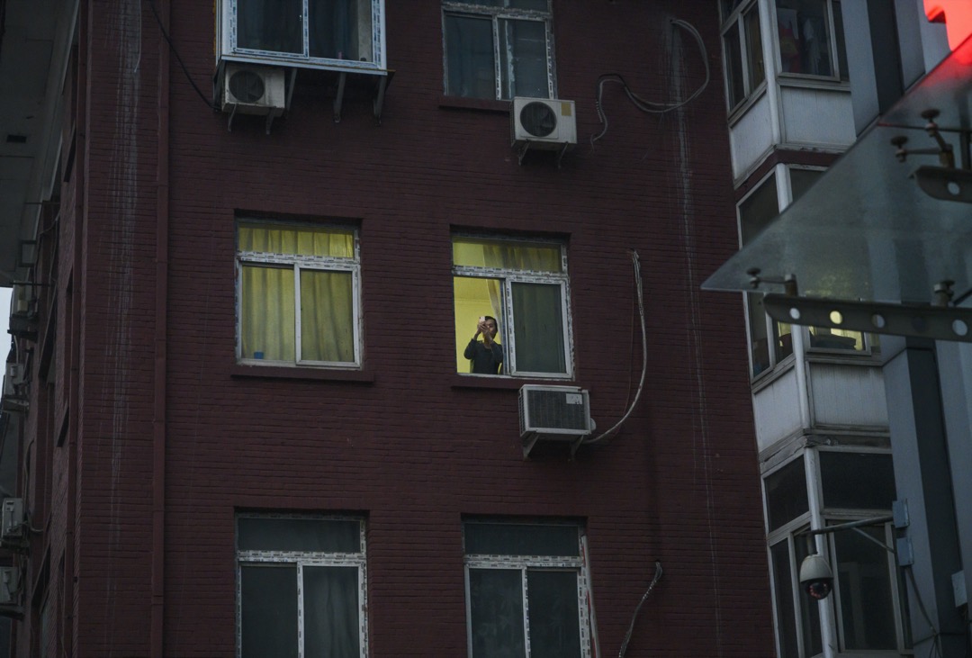 2020年3月6日,北京一所住宅內,一位男子向窗外拍攝。北京當局要求所有進入北京的人進行14天強制隔離。