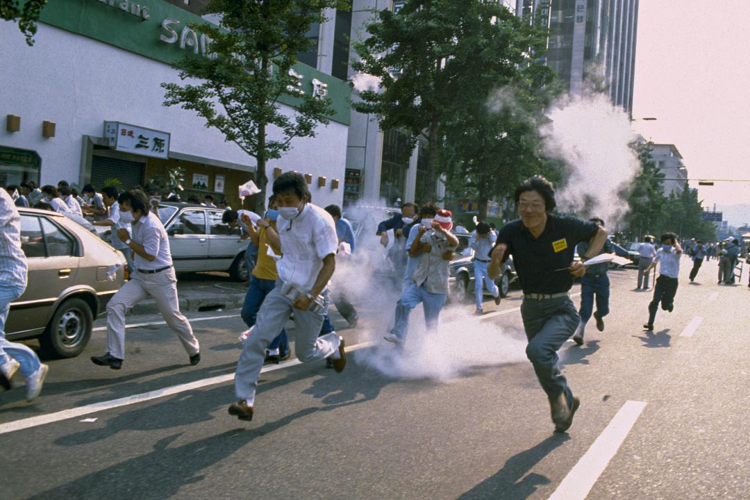 1987年6月26日,首尔街头的示威游行,学生抗议者在催泪弹中奔跑。