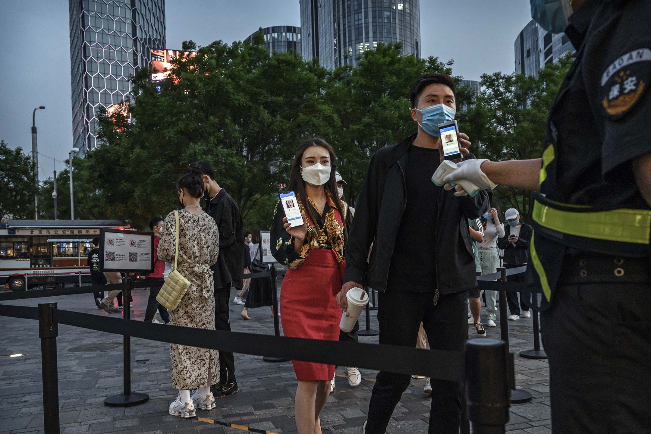 2020年5月3日北京,一名中國男人和婦女在假期期間,於進入購物中心前,一名警衛查看他們的健康碼。