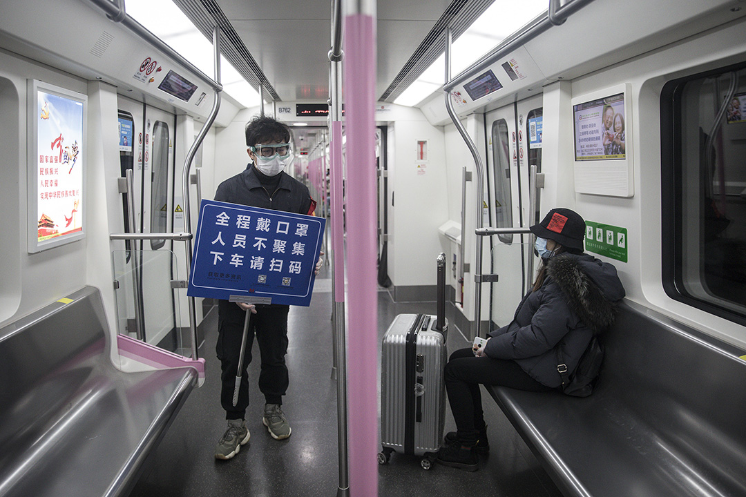 2020年3月28日武漢,地鐵工作人員舉起紙牌提醒乘客戴口罩,及掃描健康碼。