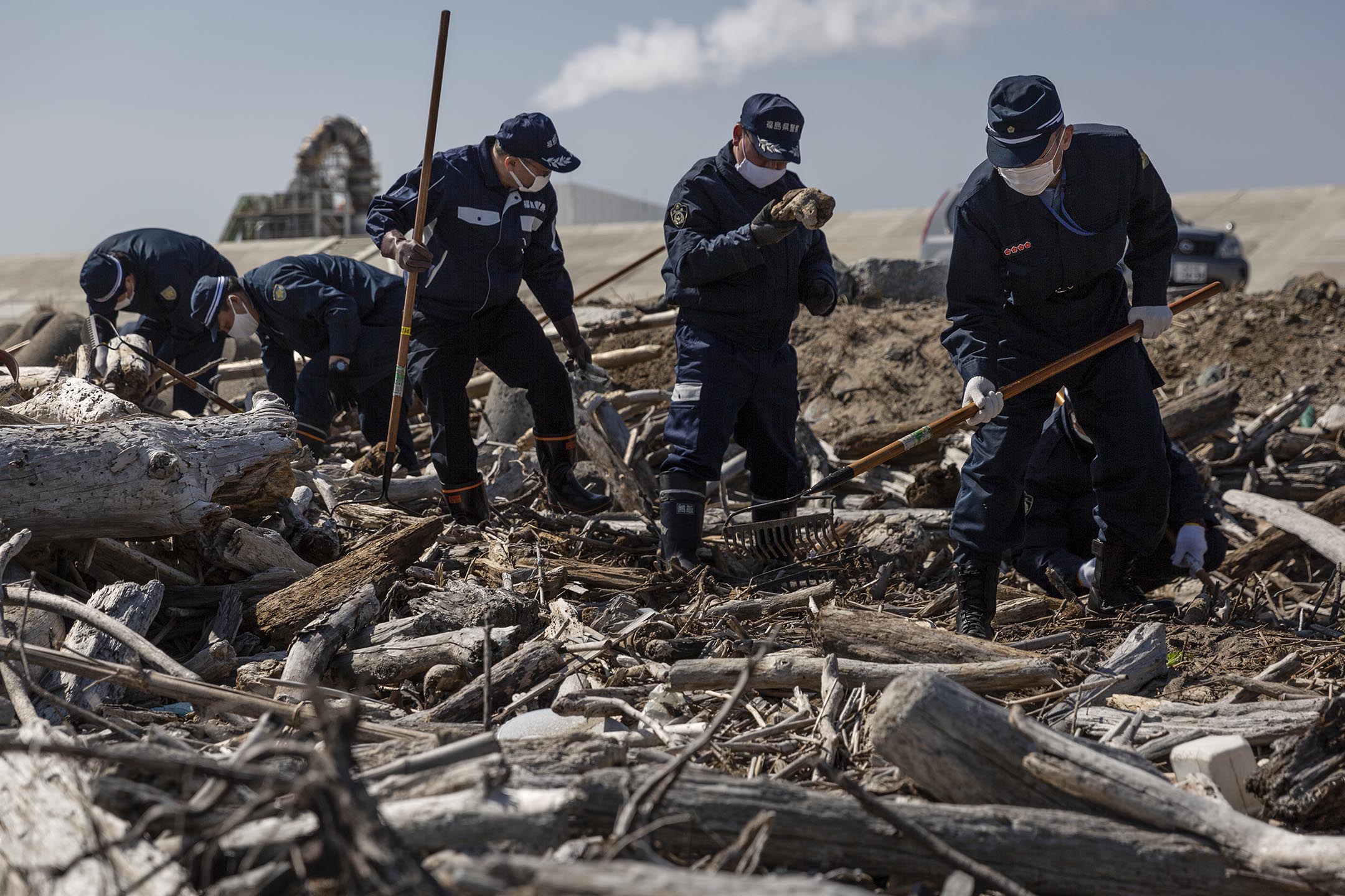 2021年3月11日,日本福岛县浪江町,警员在海边搜索十年前福岛核电厂爆炸事故中失踪者的遗体。