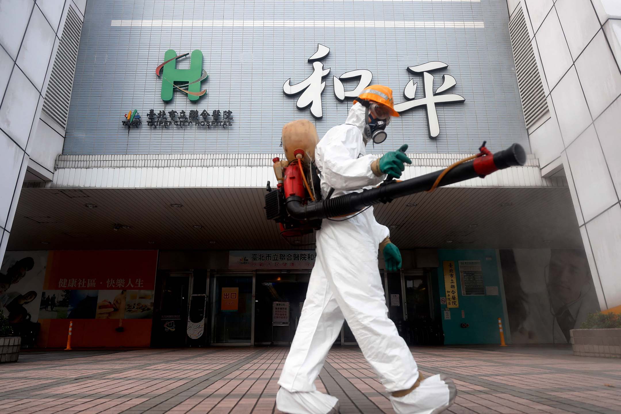 2021年5月15日，一名穿著防護裝備的工作人員為台北的和平家醫院外消毒。