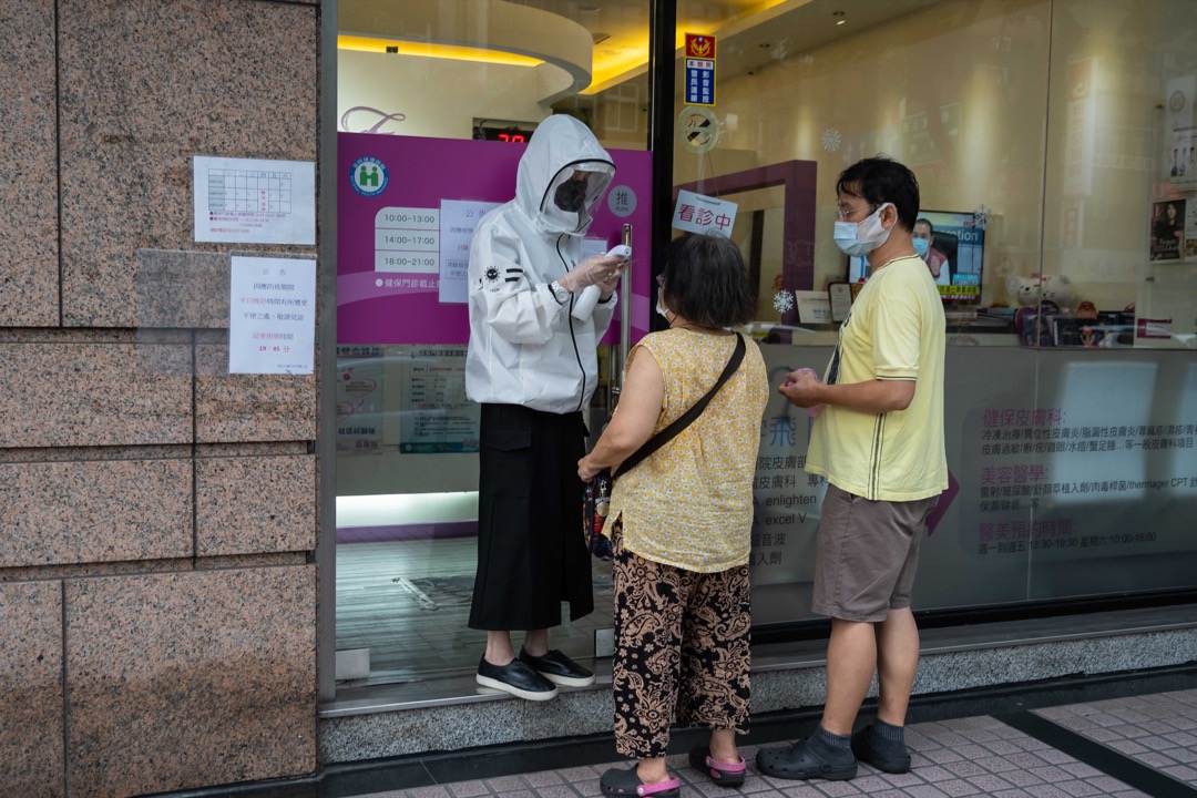 2021年5月27日,台北街頭,一名店員為顧客量度體溫。