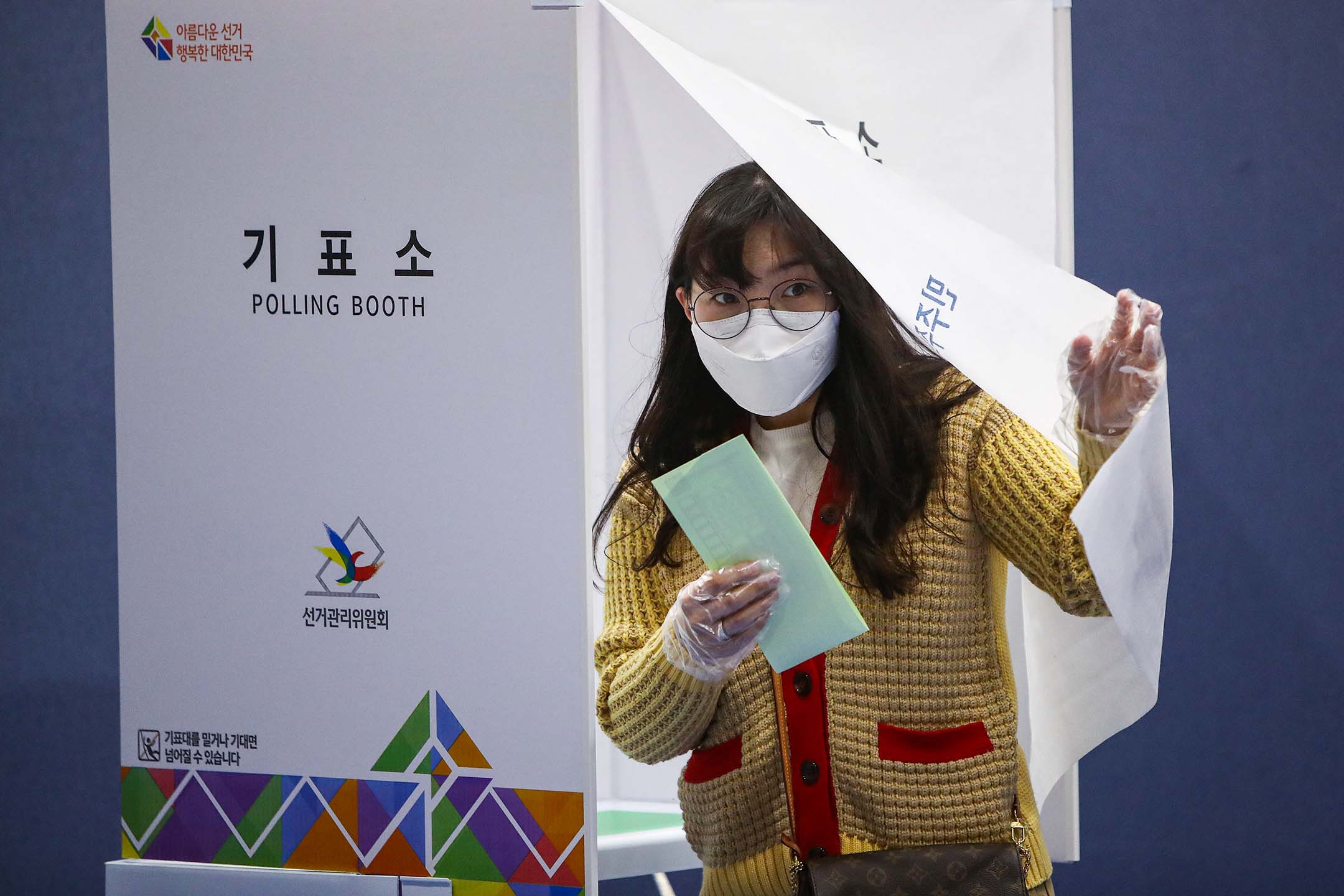 2020年4月15日韓國首爾,一名韓國婦女戴著口罩及手套在議會選舉的一個投票站內投票。